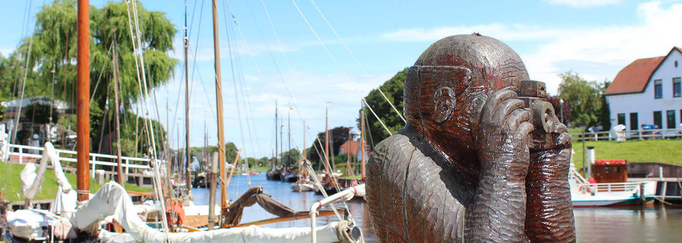 Hafenfigur vor historischen Segelschiffen im Museumshafen von Carolinensiel