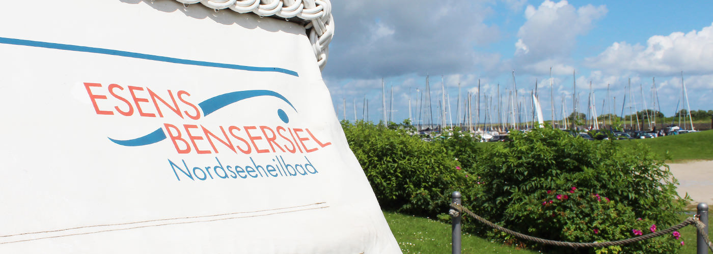 Strandkorb mit Schriftzug Esens-Bensersiel vor dem Yachthafen an der Nordsee