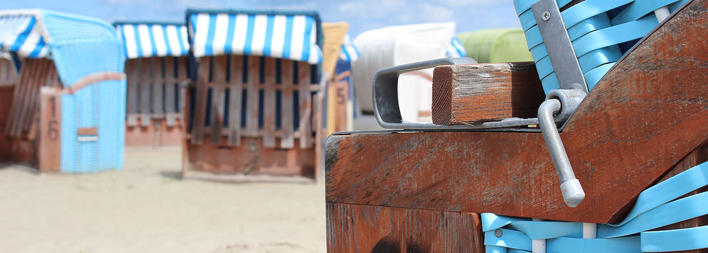 Blauer Strandkorb am Sandstrand mit weiteren Strandkörben an der Nordsee